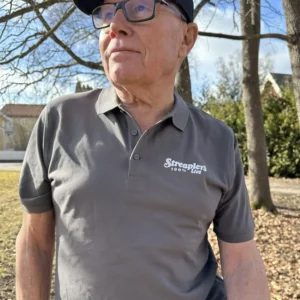 Person bär pikétröja från Streaplers egen kollektion med broderad logotyp på bröstet.